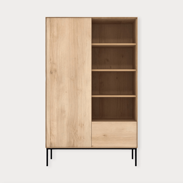 Ethnicraft Whitebird Storage Unit in natural oak with one door, one drawer, open shelves, and black metal legs.