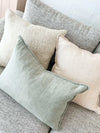 Baya Arcadia Cushion in sage green linen with flange edge on a grey textured sofa