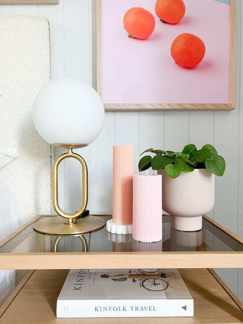 Modern brass desk lamp with frosted glass shade on wooden side table with decor items