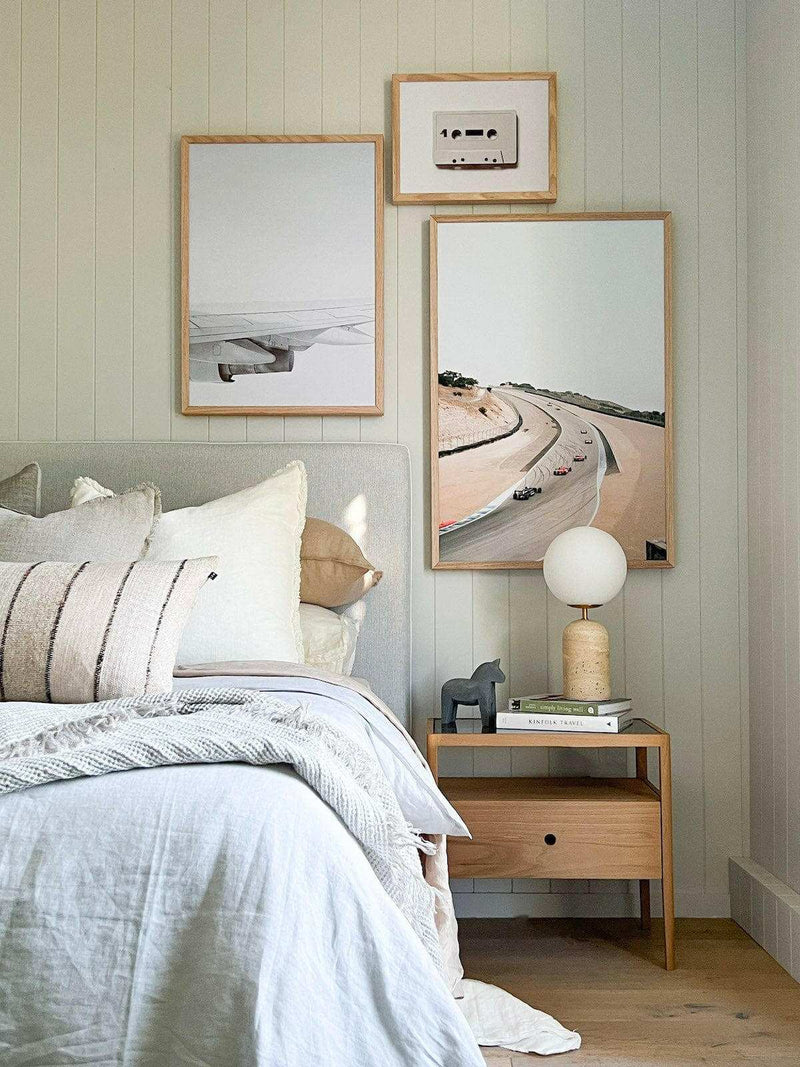 Soren Desk Lamp with travertine base, frosted glass shade, and brass details on wooden bedside table in modern bedroom setting
