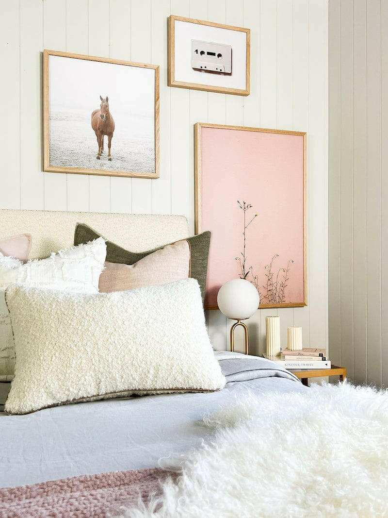 Cozy bedroom with bold inspiring wall art including a horse print and botanical photo in wooden frames above the bed
