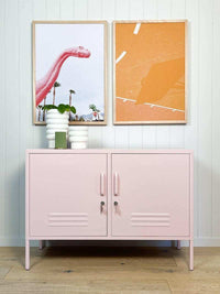 Pink Mustard Made Locker Lowdown Blush console with handles, locks, and ventilation standing against a white paneled wall with framed art.