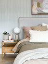 Modern brass desk lamp with frosted glass shade on wooden bedside table in cozy bedroom setting
