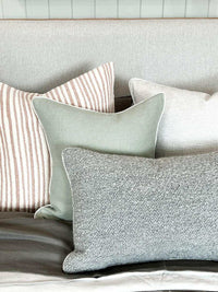 norsu Studio Cushion in haven celadon with white leather piping displayed among neutral textured decorative pillows on a sofa