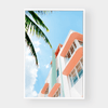 Bold inspiring wall art featuring pastel-colored building and palm tree against blue sky, available in various sizes and framing options.
