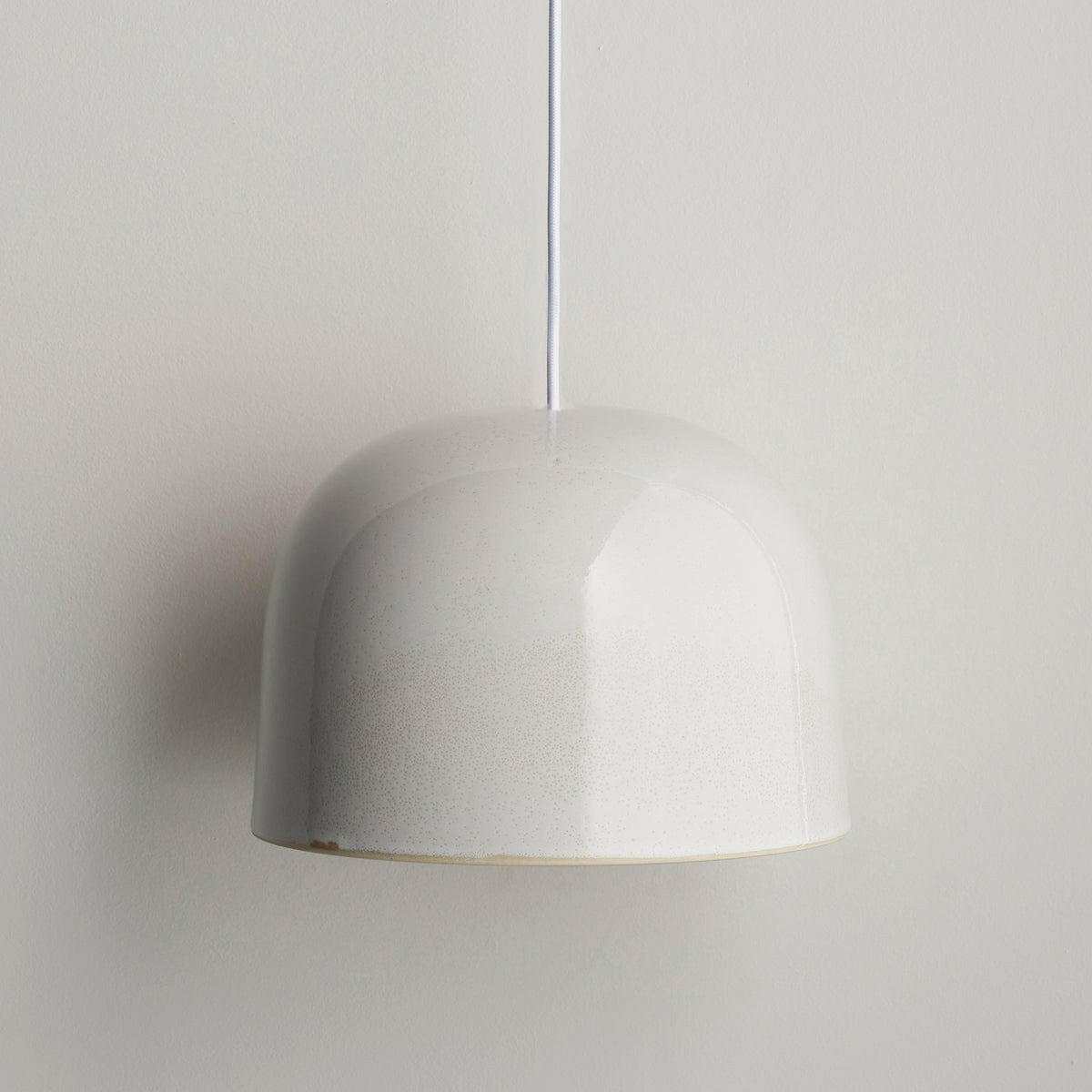Robert Gordon Bell Light large white ceramic dome pendant light hanging against a plain wall