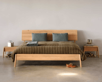 Ethnicraft Air Bed made from solid European Oak with natural finish, shown with matching bedside tables and green cushions in minimalist bedroom setting.