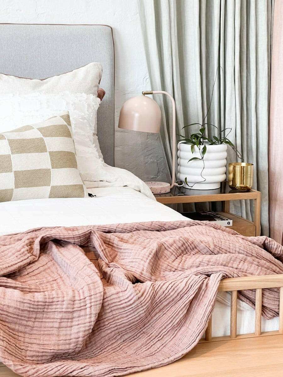 White porcelain Alder Pot with bubbly textured finish placed on wooden bedside table with plant inside in cozy bedroom setting