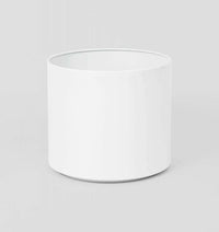 White cylindrical Benny Planter made from powder-coated stainless steel with drainage hole for indoor and outdoor use