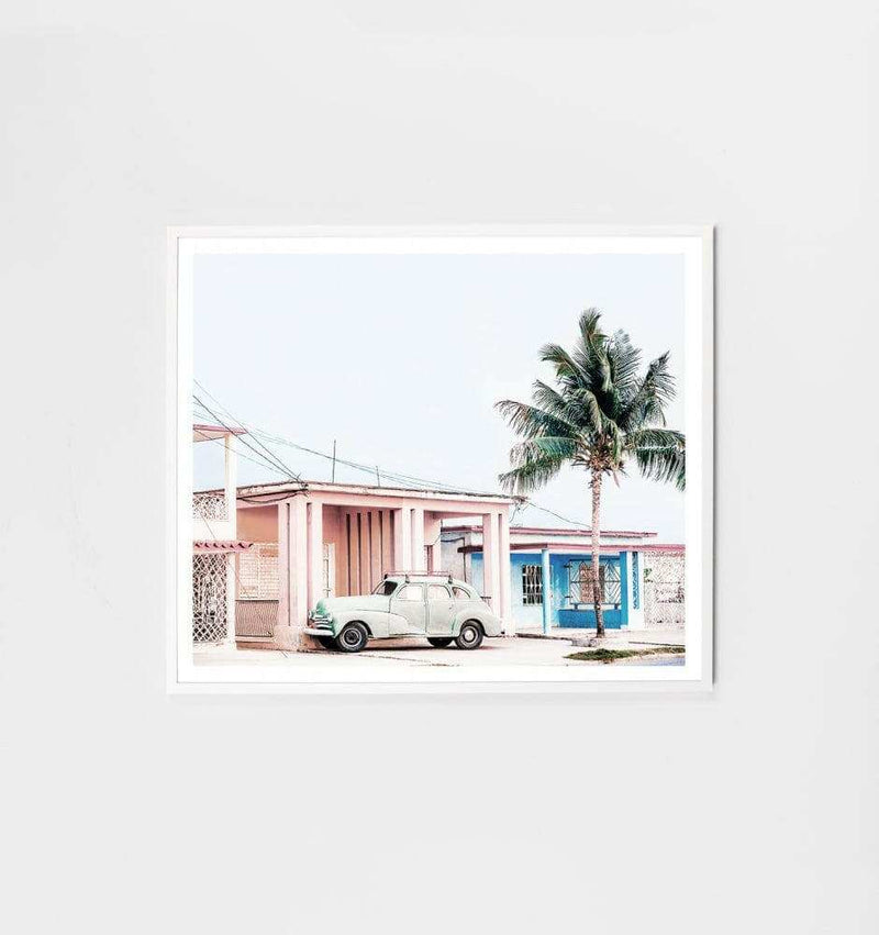 Middle of Nowhere Cuba Print featuring a vintage car and palm tree in front of pastel Cuban houses, framed in white.