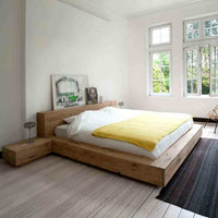 Minimalist Ethnicraft Madra Bed in natural oak with low platform and integrated side tables in a bright bedroom