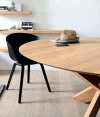 Ethnicraft Round Circle Dining Table made of natural oak with black chair in minimalist room