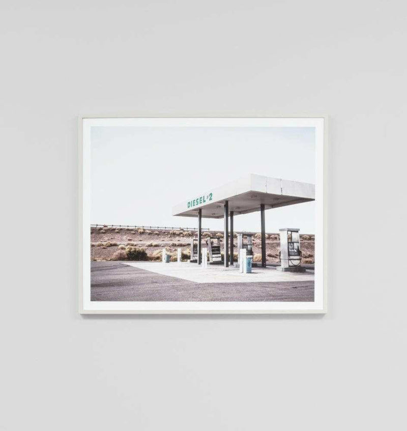 Minimalist framed print of a deserted highway gas station titled Middle Of Nowhere 'Highway' in a white frame behind glass