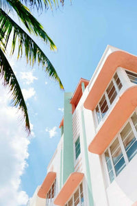 Bold inspiring wall art photo of pastel-colored building and palm tree against blue sky