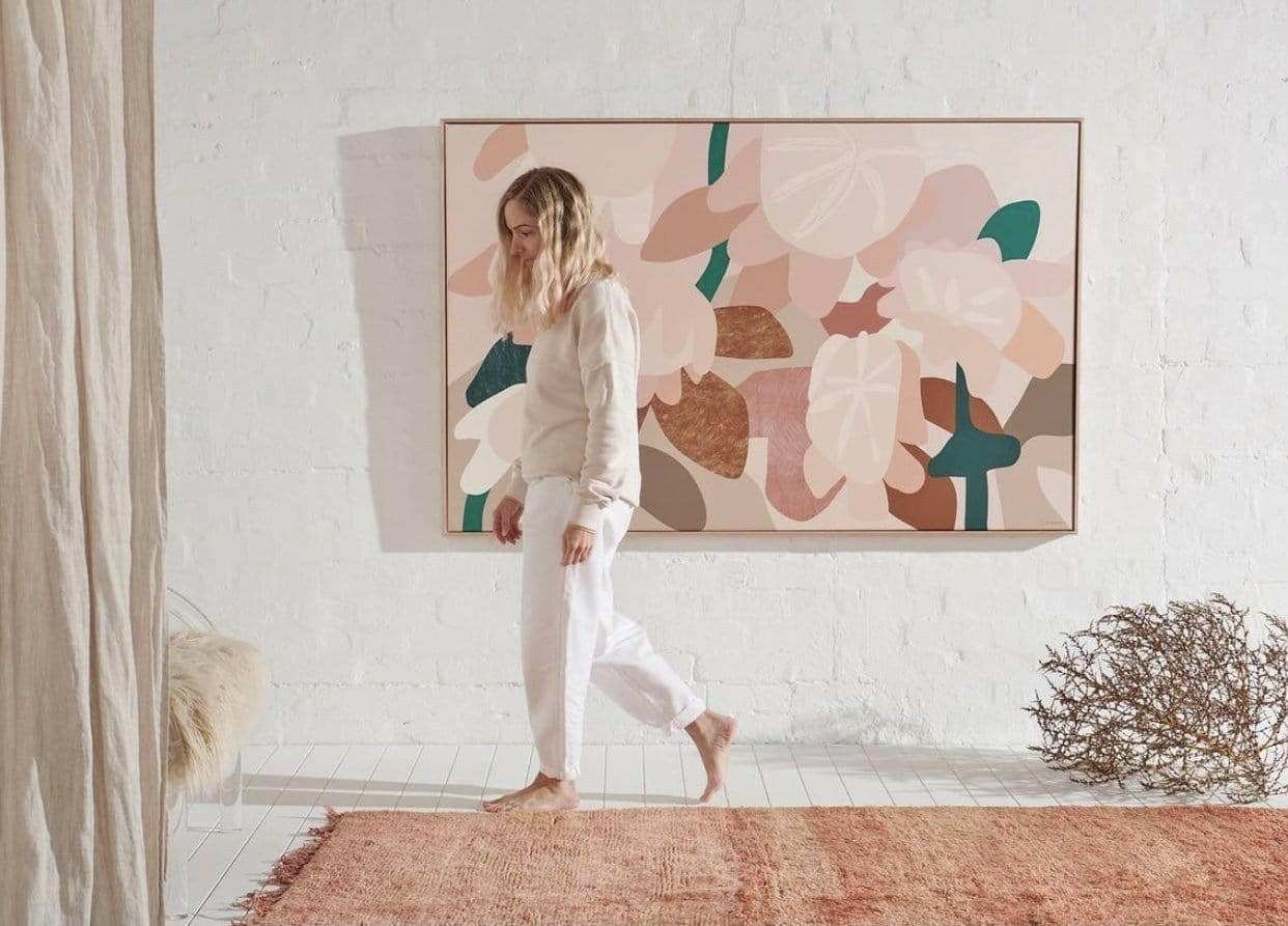 Abstract floral Kimmy Hogan Limited Edition fine art canvas print titled Dreamer hanging on white brick wall in minimalist room with woman walking barefoot on orange rug