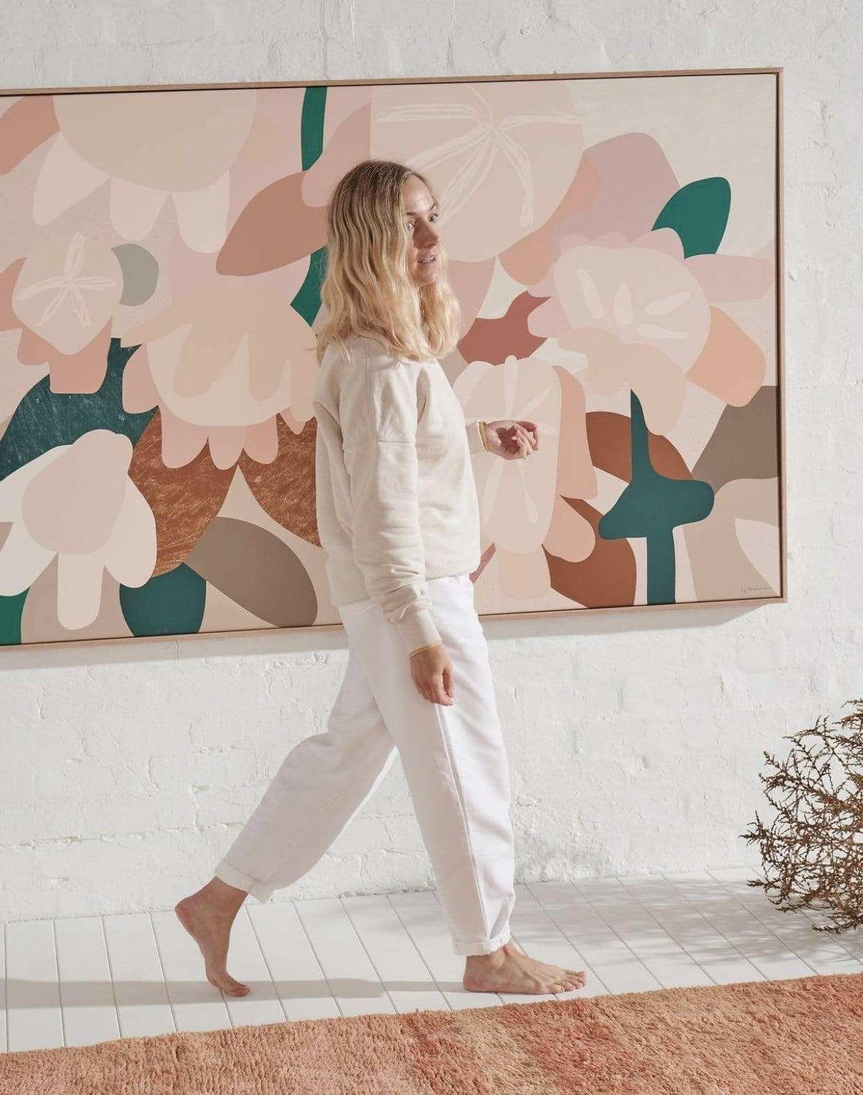 Woman walking barefoot in white outfit near large Kimmy Hogan Limited Edition abstract floral canvas print on white wall