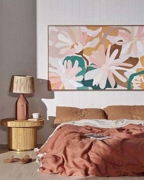 Kimmy Hogan Limited Edition Flowerbed III abstract floral canvas print in floating oak frame above bed with earthy-toned bedding and lamp on side table
