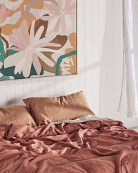Kimmy Hogan Limited Edition Flowerbed III vibrant floral canvas print above bed with brown bedding in modern bedroom