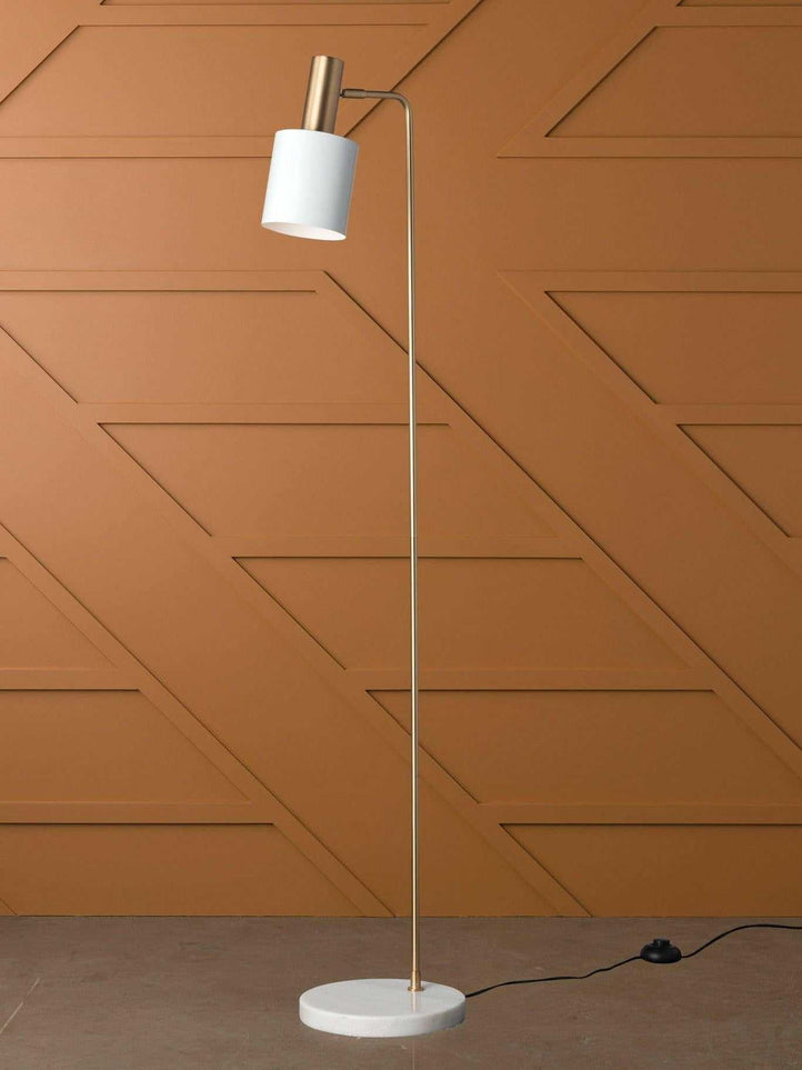 Mahala Floor Lamp with satin gold finish, white marble base, and white shade against a brown geometric wall