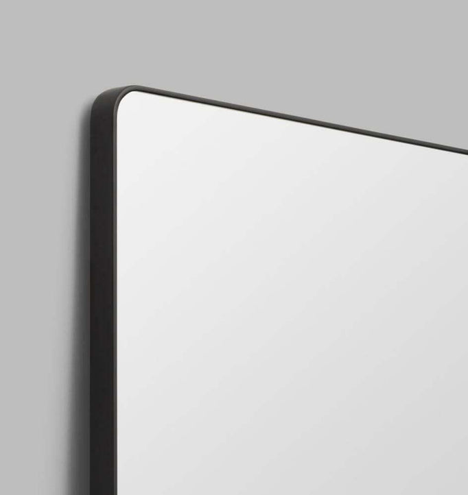 Flynn Curve Leaner Mirror with black frame and rounded corners against gray wall