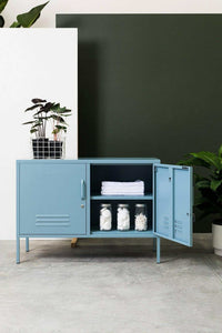 Blue Mustard Made Locker Lowdown Ocean with open door, shelves, and storage jars on concrete floor against green and white wall