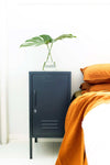 Compact shorty slate Mustard Made Locker beside bed with green leaf in glass on top