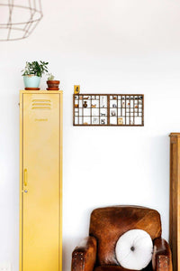 Slim mustard yellow Mustard Made Locker beside brown leather armchair with white cushion in minimalist room