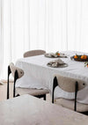Set of four Rendr 100 Linen Napkins in natural color on a white linen tablecloth with modern dining chairs