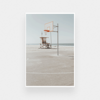 Newport Hoops Print photographic wall art featuring a basketball hoop on a beach court with a lifeguard tower in the background, available in various sizes and framing options.