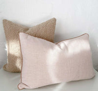norsu Studio Bouclé Buff cushion with white leather piping on light background