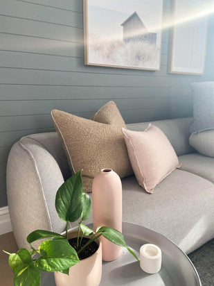 norsu Studio Bouclé Buff Cushion with white leather piping on modern sofa with plants and decor