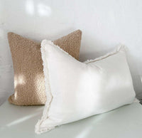 norsu Studio Bouclé Buff cushion with white leather piping and plush feather-down filling displayed in neutral tones