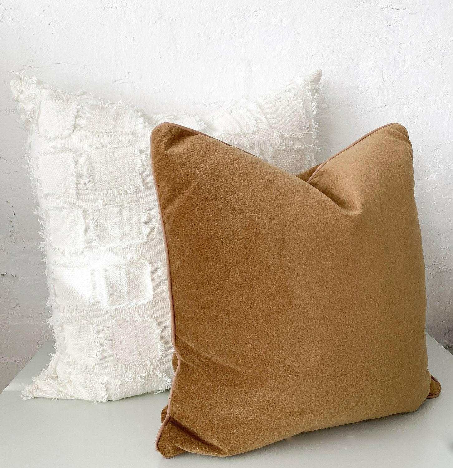 Caramel velvet norsu Studio Cushion with blush leather piping on a white textured cushion background