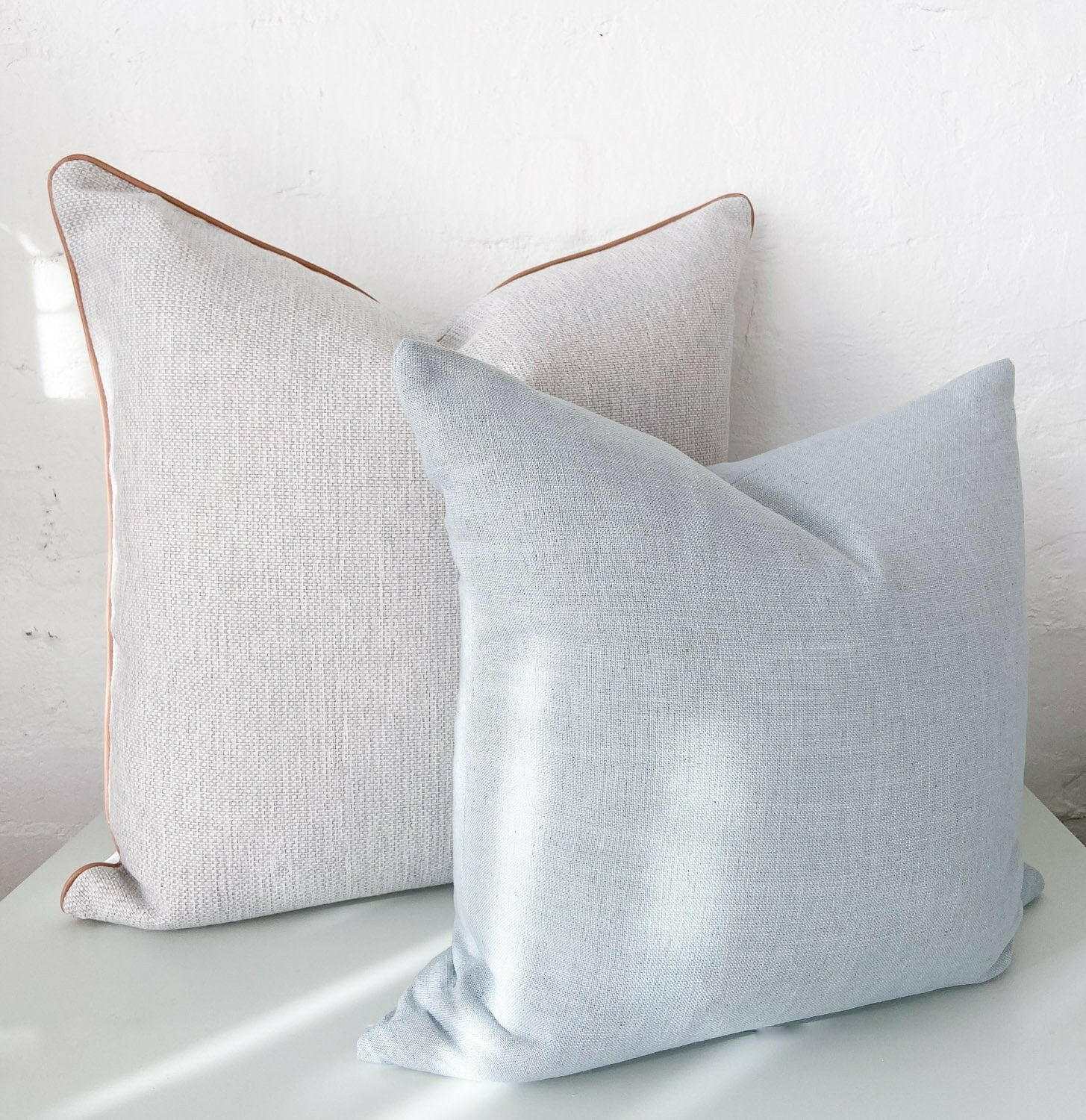 Two norsu Studio Cushions in Lexus Duck Egg color with soft fabric texture placed against a white wall