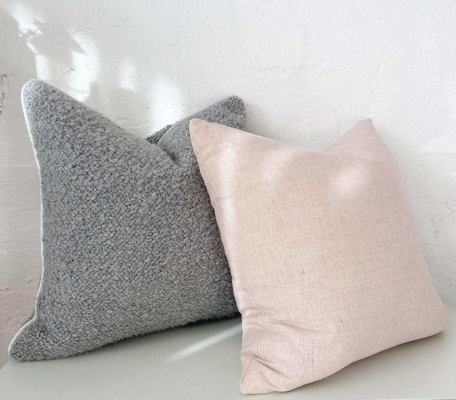 norsu cushion Lexus Rosewater in soft pink fabric and textured gray cushion side by side on white surface against white wall