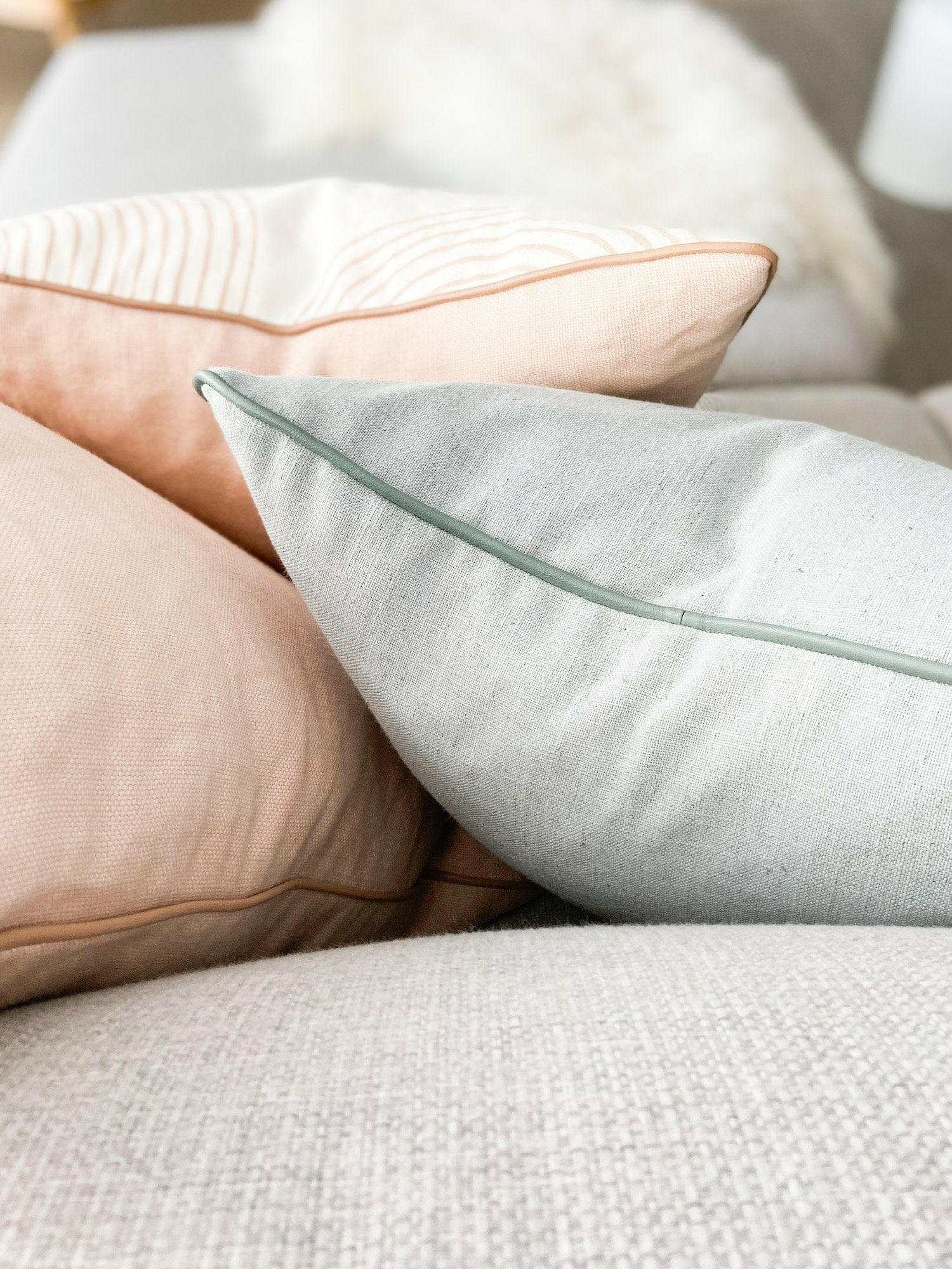 norsu Studio Cushion in Lexus Rosewater with blush leather piping on a sofa