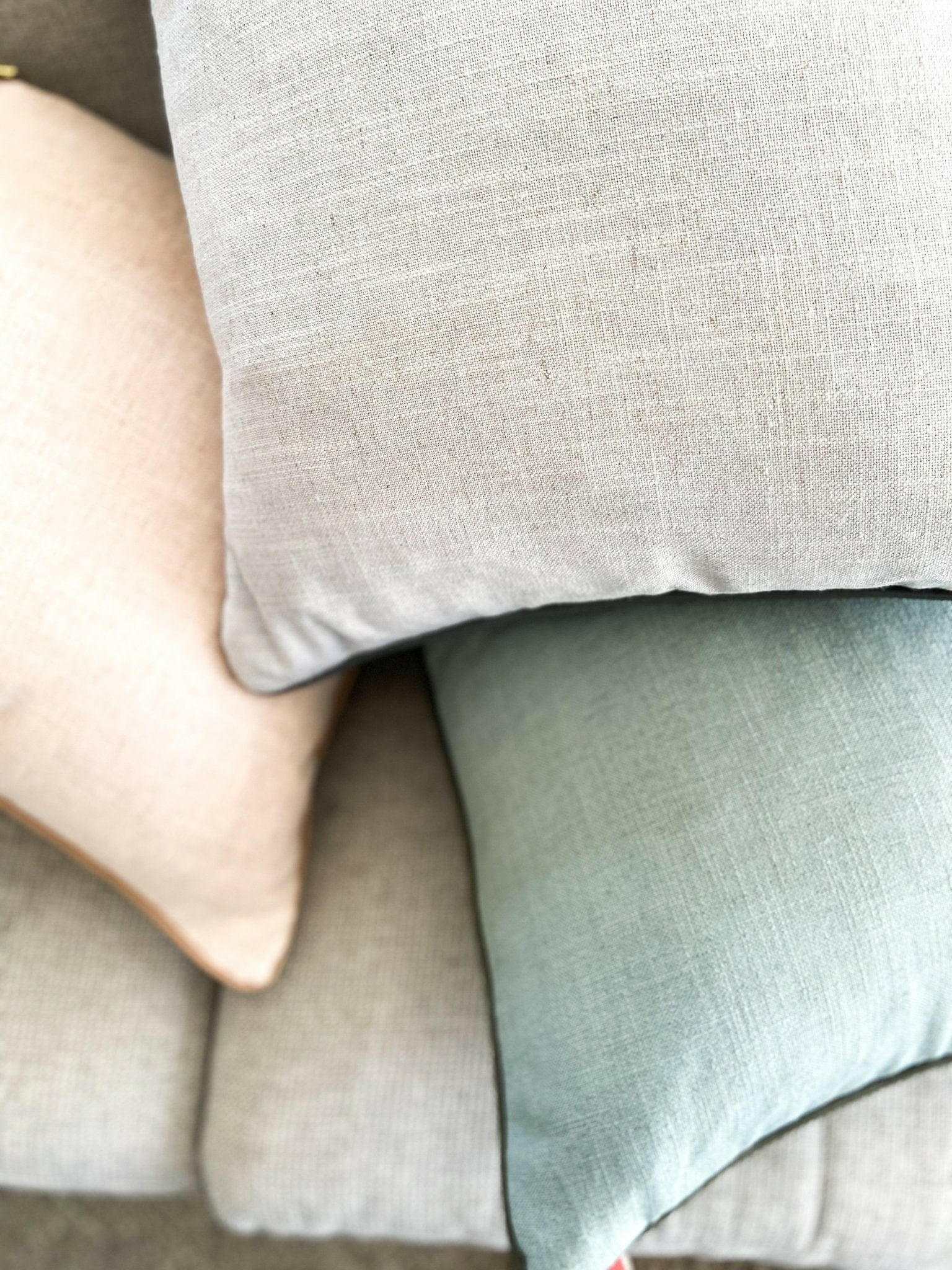 Close-up of norsu Studio Cushion in muted pastel colors with soft fabric texture and feather down filling.