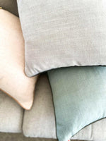 Close-up of norsu Studio Cushion in muted pastel colors with soft fabric texture and feather down filling.