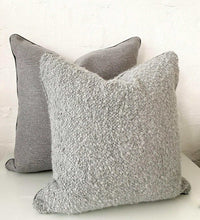 Two norsu cushions in Lindeman Steel fabric, one textured and one smooth, displayed against a white wall