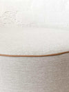 Round norsu Ottoman in Lindeman Snow fabric with blush leather piping, soft foam-filled, available in various sizes.