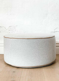 norsu Ottoman in Lindeman Snow fabric with blush leather piping, soft foam-filled round ottoman ideal for seating or footrest