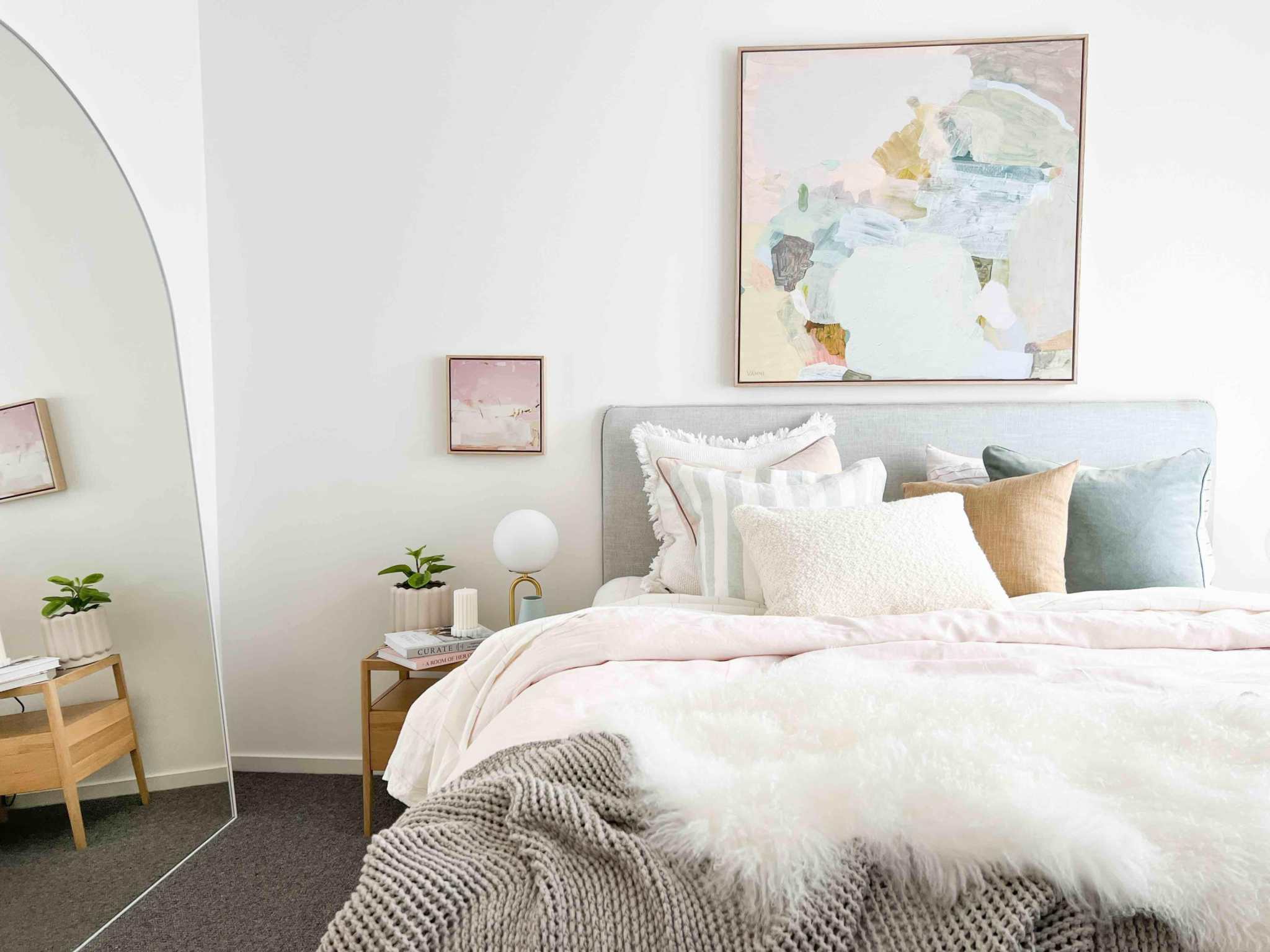 Modern bedroom with pastel-colored norsu studio washable cushions on bed and abstract wall art