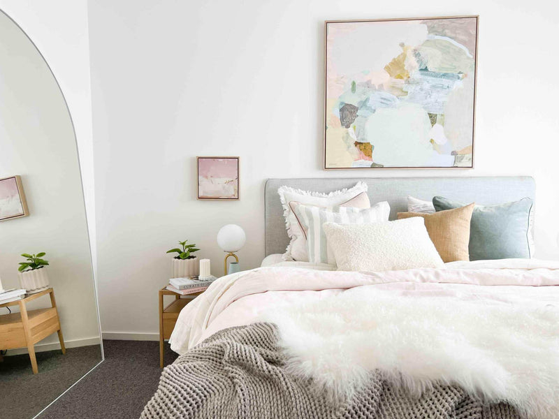 Modern bedroom with pastel-colored norsu studio washable cushions on bed and abstract wall art