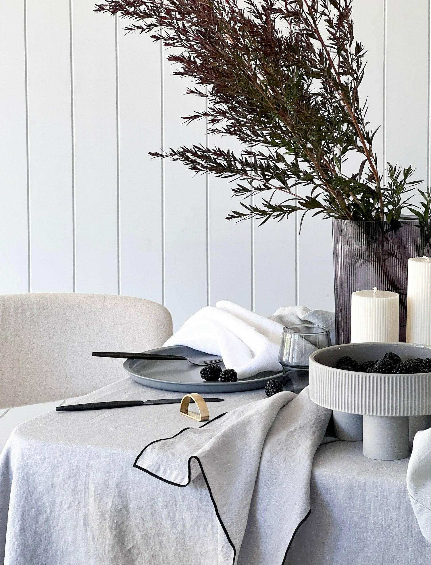 Set of four white Rendr 100% linen napkins on a dining table with tableware and decorative greenery