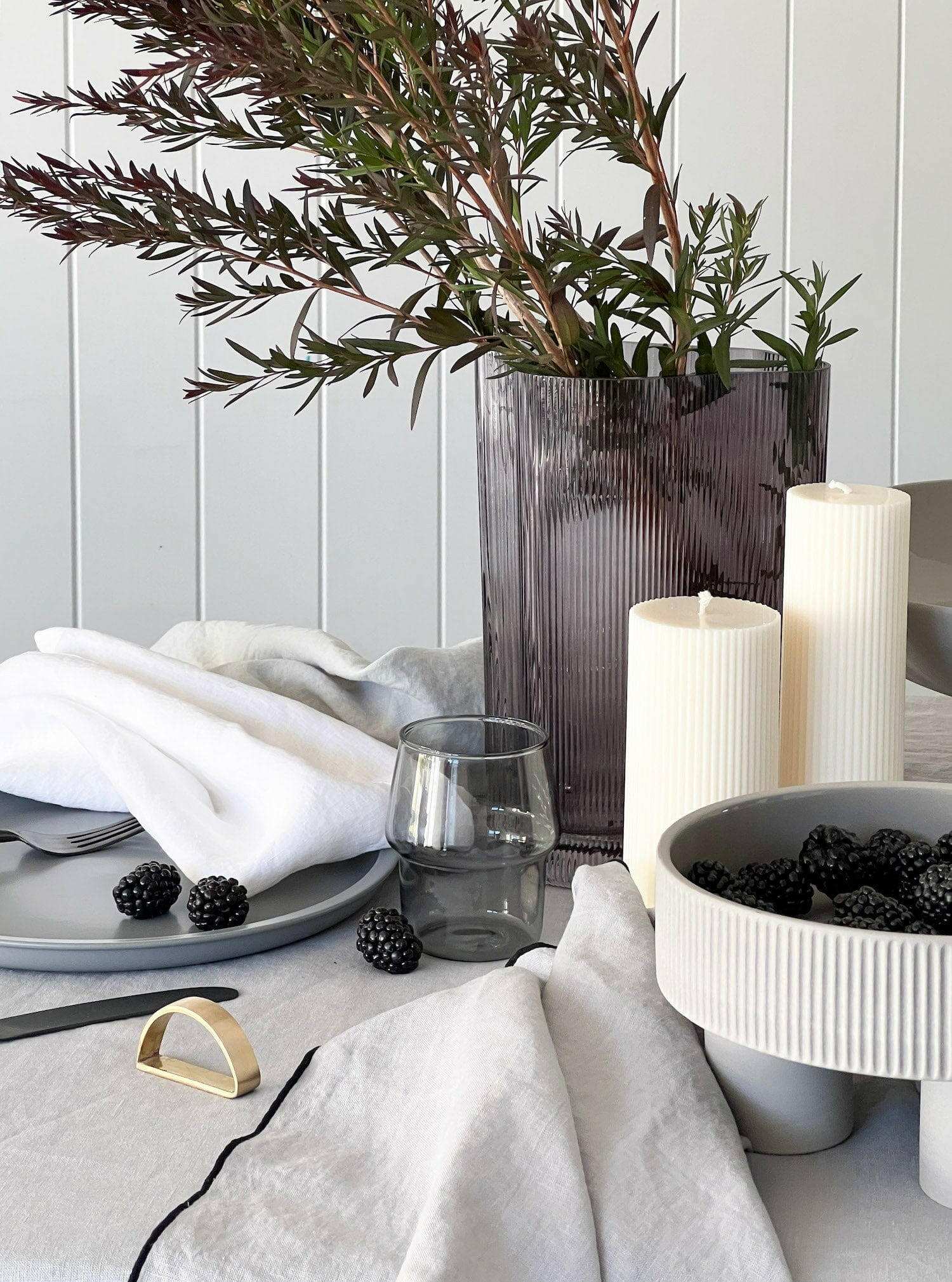 Set of four white Rendr 100% linen napkins on a dining table with grey plates, blackberries, candles, and a vase with greenery