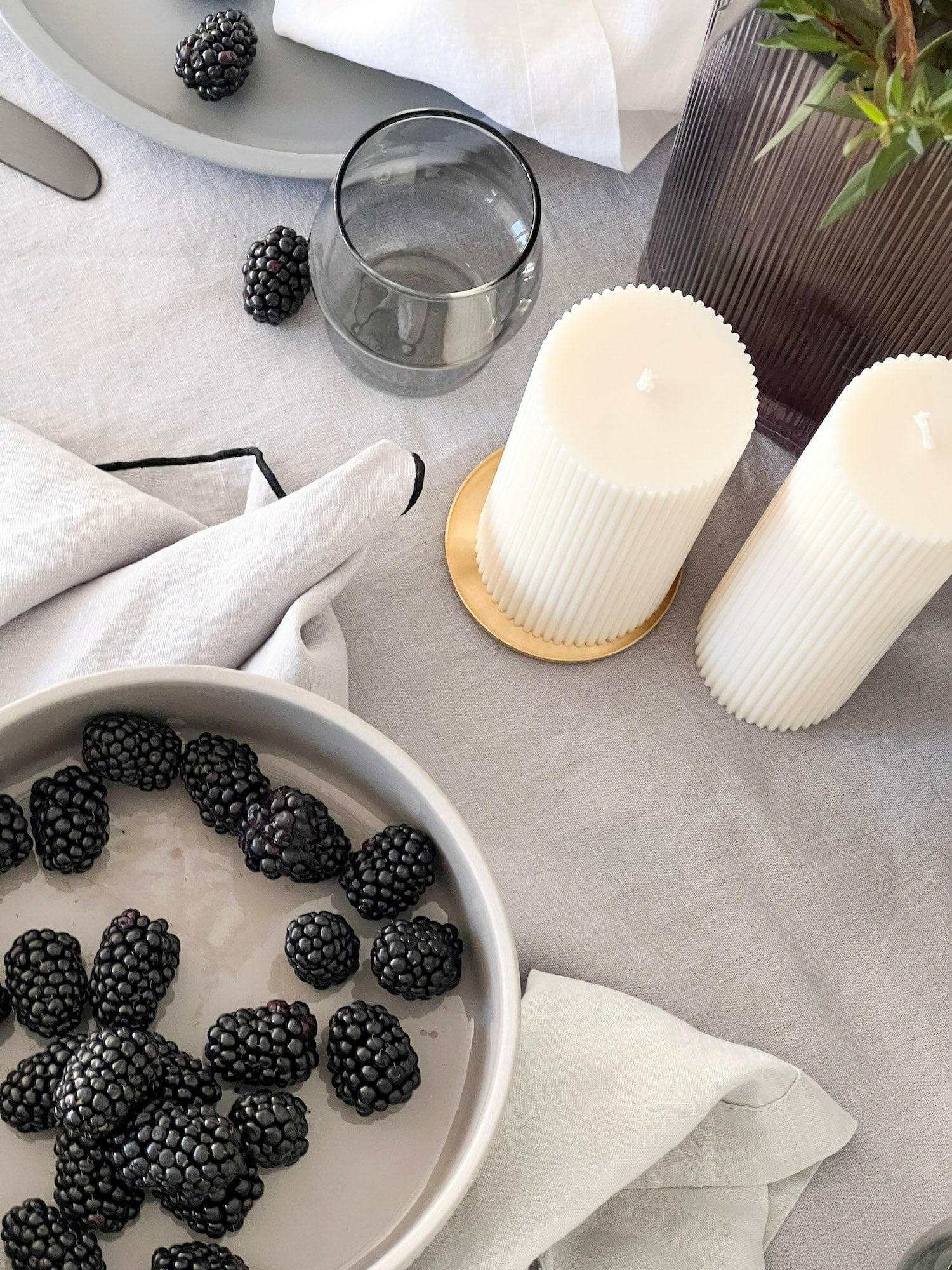 Rendr Amara Stitch 100% linen tablecloth in cool grey with contrasting embroidered edging, styled with candles and blackberries