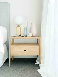 Modern brass desk lamp with frosted glass shade on wooden bedside table