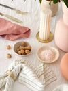 Set of four Rendr 100% linen striped olive napkins on a table with a candle, pink napkin, cutlery, nuts, and salt bowl