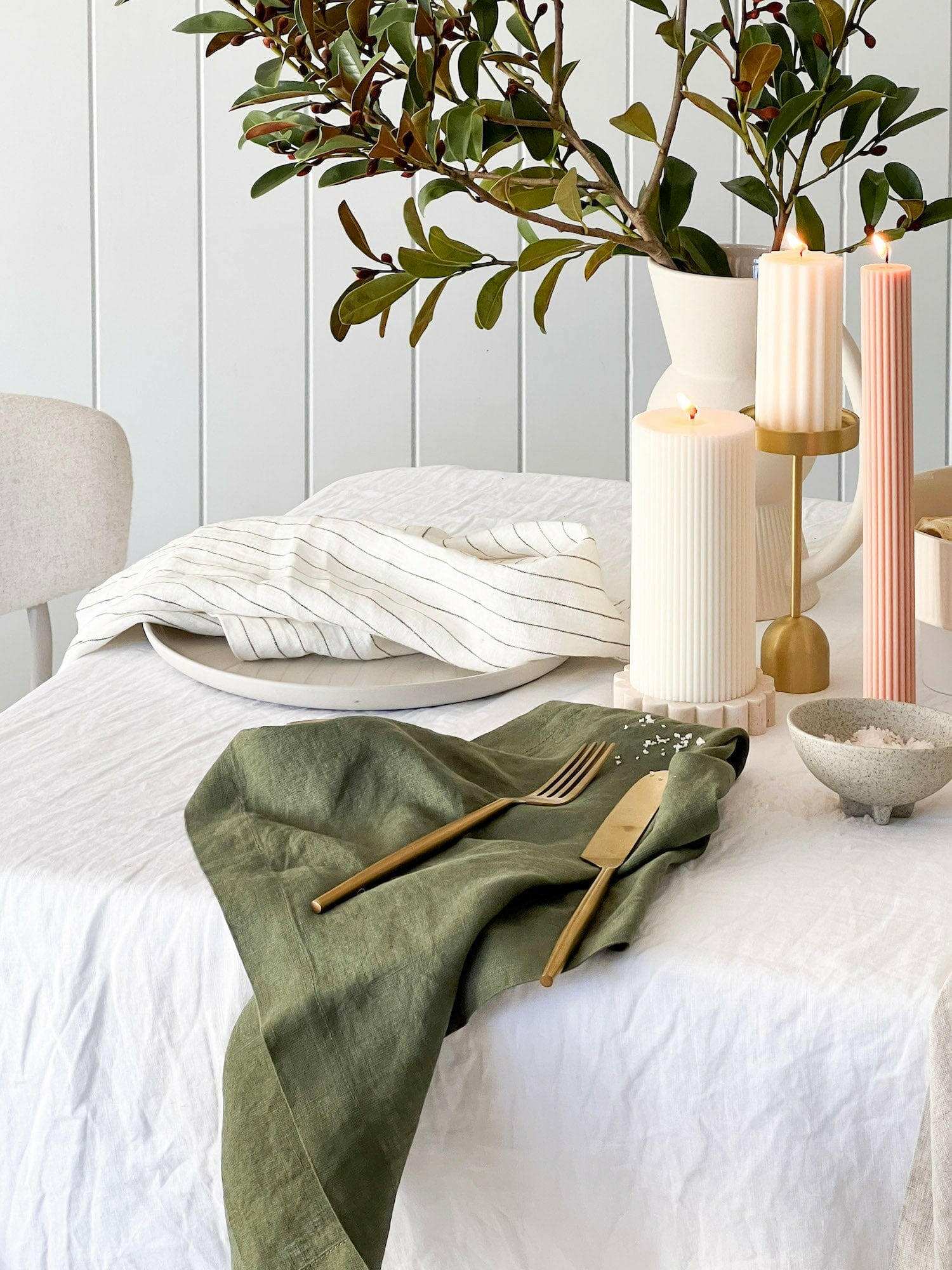Rendr 100% linen olive striped napkins set on white table with candles and greenery centerpiece