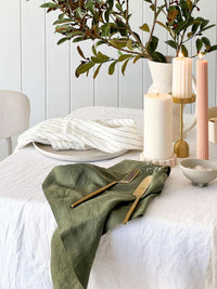 Rendr 100% linen olive striped napkins set on white table with candles and greenery centerpiece